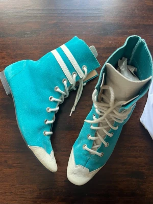 Turkosa boots med vita detaljer - Unika coola vintage boots i mocka med cool retrovibe. Perfekta för dig som vill sticka ut med färg och sportig känsla. Storleken är ca 37-38. Små skavanker men känns så fräscha. Snörena har fläckar(som på bilden) som kanske går bort vid tvätt. 