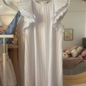 Vit plisserad klänning med volang - Säljer en vit plisserad klänning med breda volangärmar. Storlek XS/S!!! Så fin o passar perfekt till studenten💕💕
