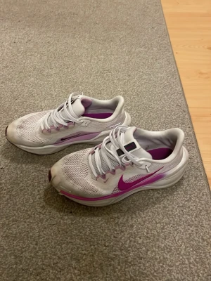 Nike Pegasus 41 - Snygga vita sneakers från Nike med lila detaljer och swoosh på sidan. Skorna har mesh-ovandel för bra ventilation, vita skosnören och en bekväm sula. Perfekta för dig som gillar sportig stil och vill ha något som sticker ut. Otroligt sköna och snygga. 