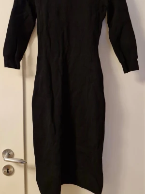 Svart långklänning J.Lindeberg, storlek XS - Snygg svart långklänning från J.Lindeberg med lång ärm och figurnära passform. Klänningen är ribbad och har en enkel, stilren design som passar perfekt till många olika tillfällen. Storleken är i XS.