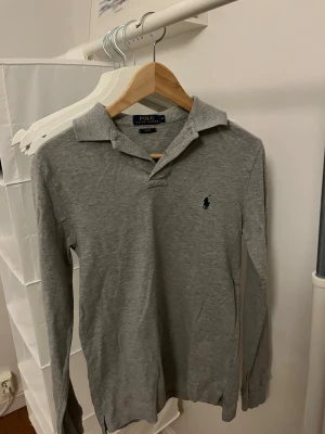 Grå långärmad piké från Polo Ralph Lauren - Klassisk grå långärmad pikétröja från Polo Ralph Lauren. Den är i bra skick och är i storlek S. 