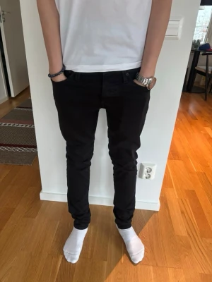Svarta slim fit jeans från Jack & Jones - Säljer ett par svarta slim fit jeans med klassisk femficksdesign och normal midja. Jeansen har smal passform hela vägen ner och är perfekta för en clean och stilren look. Passar dig som gillar en enkel men snygg stil.