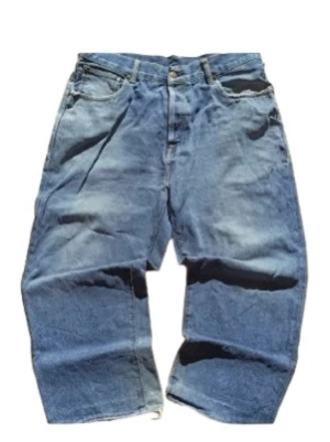Evisu baggy jeans - Unika baggy jeans från Evisu i blå denim med handmålat gult måsmotiv på baksidan. Klassisk femficksmodell, raka och vida ben med croppad längd. 100% bomull och coola kontrastsömmar. Perfekta för dig som vill sticka ut med streetwear-vibe. För mer information, bilder och prisdiskutering i dm. Äkta