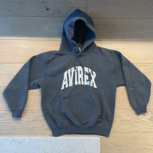 Avirex Hoodie - Är lite kortare i passform, passar S-M. Lite smuts på vänster ärm som ses på första bilden.        Längd: 62,5 cm Bröst: 53 cm Ärm: 54 cm Hem: 40 cm