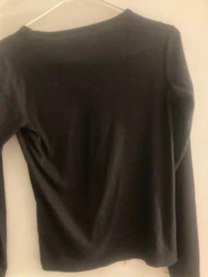 Svart långärmad tröja basic - En enkel svart långärmad tröja med rund halsringning. Tröjan har en rak passform och är tillverkad i ett mjukt och stretchigt material, perfekt för lager-på-lager eller som basplagg.