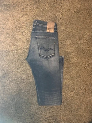 Blå Replay jeans med raka ben - Snygga blå jeans från Replay med raka ben och klassiska bakfickor med dekorativ söm. Jeansen har en lätt tvättad look och läderpatch med logga bak i midjan. Perfekta för en avslappnad stil. 