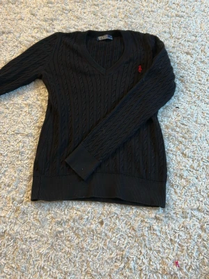 Svart stickad Polo Ralph Lauren tröja - Hej, säljer min svarta stickade tröja med rött Ralph lauren märke. (Inte äkta). Säljer eftersom den inte kommer till användning. Och har bara använt den ett  fåtal gånger. 
