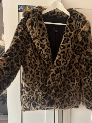 Leopardmönstrad fuskpälsjacka - Fluffig pälsjacka från Forever 21. Bild 1 är tagen av personen jag köpte jackan av. Ännu ett plagg som ingick i min halloweenklädnad, har inte användning av längre. Den har fickor. Ingen knapp eller liknande för att stäcka framtill.🐆