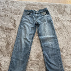 Blå raka jeans från Levi's - Klassiska blå jeans från Levi's med rak passform och fem fickor. Jeansen har en ljus tvätt med lätt slitning på låren och bakfickor med den ikoniska Levi's-detaljen. Perfekta för en avslappnad och stilren look.
