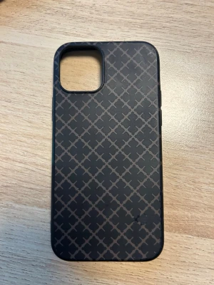 Brunt mobilskal By Malene Birger ip12 - Snyggt brunt mobilskal från By Malene Birger med ett stilrent geometriskt mönster i grått. Skalets material känns tåligt och har en matt finish. Passar perfekt för dig som vill ha ett trendigt och skyddande skal till din mobil.