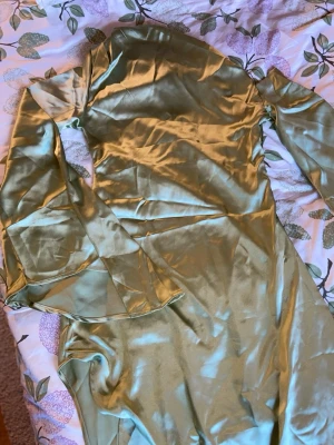 Lång one shoulder satinklänning med utsvängda ärmar - Snygg långklänning i glansigt grönt satinmaterial med långa, utsvängda ärmar. Aldrig använt!