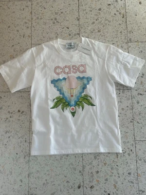 Casablanca T-shirt - vit/rosa/blå - Väldigt unik Casablanca t shirt, för den som vill sticka ut i sommar. Den är helt ny med tagsen på, och säljs för ett väldigt bra pris. Tveka inte på att fråga vid funderingar!