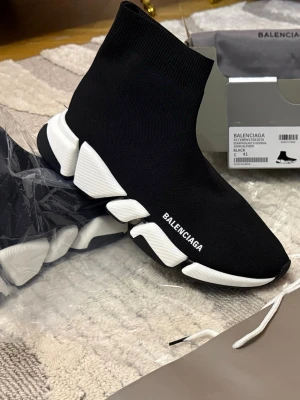 Balenciaga Speed Trainer svarta sneakers - Svarta Balenciaga Speed Trainer sneakers med vit chunky sula och stickad ovandel i textil. Strumpliknande passform och tydlig logga på sidan. Modern och sportig design som sticker ut med sin unika sula och minimalistiska look.