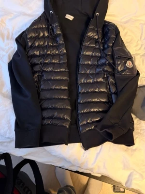Mörkblå cardigan med huva från Moncler - Snygg mörkblå cardigan från Moncler med glansig vadderad front och mjuka ärmar. Storlek M, men passar S också.  Slå ett PM för mer bilder, pris går att diskutera. 