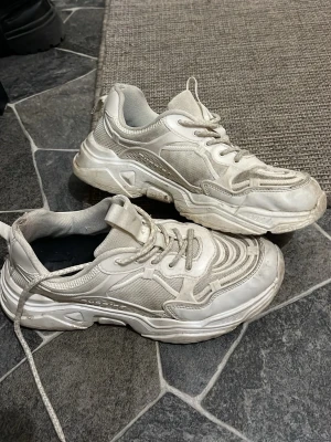 Chunky vita sneakers - Säljer ett par chunky vita sneakers . Skorna har tjock sula och snörning framtill. Perfekta för dig som gillar streetwear och vill ha en trendig look. Passar till det mesta och ger en sportig vibe.