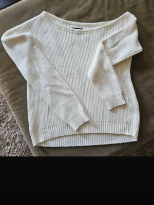 Vit ribbad stickad tröja  - Snygg vit stickad tröja från Even and odd med ribbad struktur och off shoulder-design. Tröjan har långa ärmar och en avslappnad passform, perfekt att styla med jeans eller kjol. Enkel och stilren look som funkar året runt.