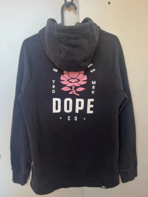 Svart hoodie från Dope med tryck - Svart hoodie från Dope! Perfekt för dig som gillar streetwear och snygga tryck. Tröjan e använd få tal gånger