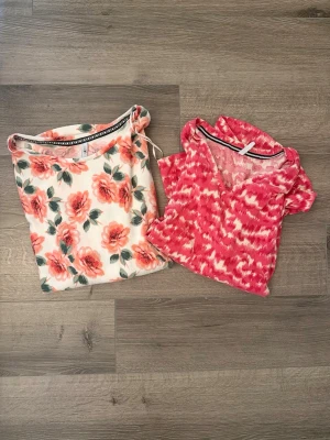 Hailys 2pack tröjor sommar - Topp 1: En supermjuk ljus tröja med romantiskt blommönster i korallrosa/persika. Mjuk och god stretchig kvalitet med fin passform. Topp 2: En mjuk tröja i "pink ikat/tie-dye"-mönster med smickrande V-ringning. Längre baktill.   Båda tröjor är i storlek S och material 95% polyester 5% elastan. Fina till ljusa jeans inför sommaren.