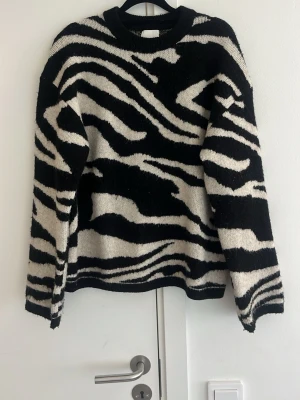 Zebramönstrad stickad tröja H&M - stickad tröja från H&M med svartvitt zebramönster. Tröjan har rund halsringning och långa ärmar. Perfekt för dig som vill sticka ut med en trendig och djurinspirerad look. Materialet är mjukt och sticker inte.