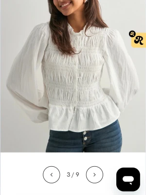 Vit blus med puffärmar och smock - Superfin vit blus med smockad överdel och breda puffiga långärmar. Blusen har en lätt volang nertill och rund halsringning. Perfekt att styla med jeans för en trendig look. Säljer den eftersom jag vill köpa den k en mindre storlek. Använt den en gång så den är som ny💞