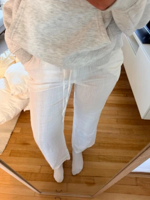 Vita linnebyxor med dragsko - Säljer ett par vita linnebyxor från med avslappnad passform och dragsko i midjan. Byxorna är raka i modellen och har fickor på sidorna. Perfekta för en chill och stilren look. Materialet är svalt och luftigt linne.