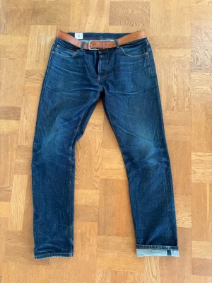 Selvedge jeans  - Jag på bilden är 189/ 87 kg och de sitter perfekt. Snygga mörkblå jeans i klassisk rak modell med fem fickor och kontrastsömmar. Jeansen är tillverkade i denim. Perfekta för en avslappnad och stilren look.