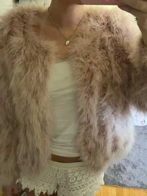 Rosa fluffig pälsjacka från WOS - Supermjuk och fluffig Rosa pälsjacka från WOS. Jackan har en öppen design utan synliga knappar eller dragkedja och är helfodrad på insidan man kan stänga den. Perfekt för dig som vill ha en mysig och trendig look med extra volym.