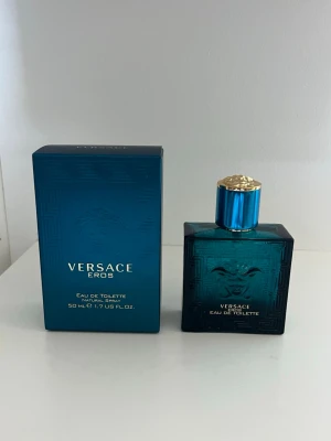 TOM/ SLUT Versace Eros Eau de Toilette 50ml - Versace Eros Eau de Toilette i en snygg turkosblå glasflaska med guldigt lock och klassisk Medusa-detalj. Flaskan rymmer 50 ml och kommer i matchande blå kartong med guldtext. En ikonisk doft från Versace. TOM 