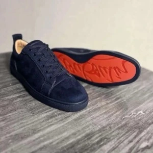 Mörkblå Louboutin sneakers med röd sula - Snygga mörkblå sneakers från Christian Louboutin med den ikoniska röda sulan som ger en exklusiv touch. Klassisk låg modell med ovandel i mjuk mocka och stilren ton-i-ton-snörning. Diskret logga undertill för en subtil premiumkänsla.  Skorna är i nyskick och endast använda två gånger. Perfekta för dig som vill sticka ut med eleganta detaljer och tidlös stil.  Kan tänka mig byte mot sneakers från Axel Arigato, helst en modell med dragkedja.