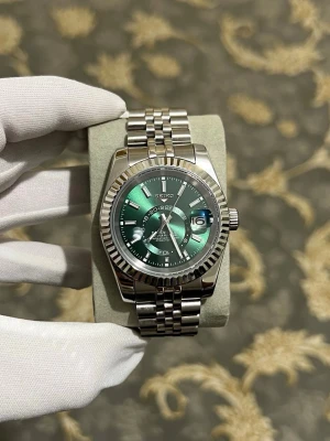 Seiko datejust sky dweller  - Snygg Seiko klocka med grön urtavla och datumvisning. Klockan har ett klassiskt silverfärgat armband i rostfritt stål och en räfflad bezel. Perfekt accessoar för dig som vill sticka ut med stilren design och cool färg på urtavlan.