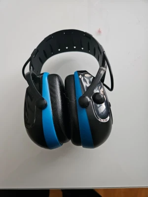 Raptor hörselkåpor svart/blå - Säljer ett par svarta och blå hörselkåpor från Raptor, modell ONE EARMUFFS. De har justerbart huvudband i plast och mjuka öronkuddar för bekväm användning. Perfekta för att dämpa höga ljud vid konserter, byggarbetsplatser eller studier. Är Bluetooth o telefon i dom med laddas med usb kabel 