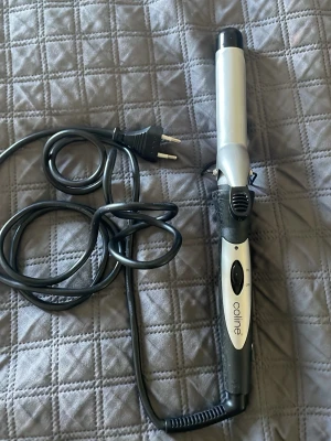 Locktång från Coline, svart och silver - Locktång från Coline i svart och silver med rund form och greppvänligt handtag. Utrustad med klämma och lång svart sladd med EU-kontakt. Perfekt för att skapa snygga lockar och vågor. Tillverkad i plast och metall.