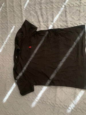 Svart t-shirt från Ralph Lauren - Svart t-shirt från Ralph Lauren med klassisk passform och korta ärmar. Liten röd broderad logga på bröstet. Perfekt basplagg med stilren look.
