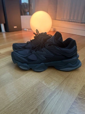 Svarta New Balance sneakers - Snygga svarta sneakers från New Balance med chunky sula och meshdetaljer. Skorna har en sportig design med flera lager av material och klassiska NB-loggan på sidan. Perfekta för dig som gillar streetwear och vill ha bekväma skor med cool look.