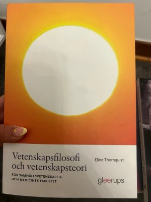 Vetenskapsfilosofi och vetenskapsteori - Kursbok i vetenskapsfilosofi och vetenskapsteori av Eline Thornquist. Omslaget är orange och vitt med en stor vit cirkel i mitten. Boken är tryckt av Gleerups och riktar sig till samhällsvetenskaplig och medicinsk fakultet.