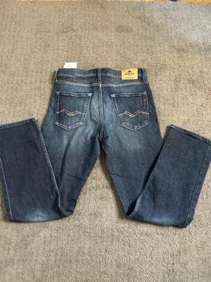 Blå jeans från Replay med raka ben - Snygga blå jeans från Replay med klassisk femficksdesign och raka ben. Jeansen har dekorativa sömmar på bakfickorna och en läderpatch med Replay-logga i midjan. Perfekta för en avslappnad och trendig look.