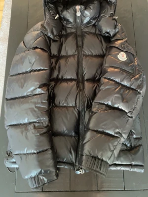 Moncler Maya - Säljer nu denna Moncler Maya! Jackan är i bra skick och håller dig varm under höst, vinter och våren. Det enda slitaget är ett litet hål som är under armen på jackan vilket då inte syns. Har även satt en laglapp som smälter in med jackan. Storleken är m=2. För fler frågor eller bilder är det bara att skriva!