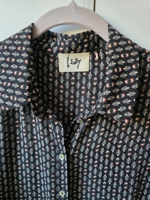 Tunn mönstrad blus från Isay - Snygg svart blus från Isay med vitt och rödbrunt bladmönster. Blusen har klassisk krage, knäppning framtill och långa ärmar med smock vid ärmslut. Tunt och lätt material som ger en luftig känsla.
