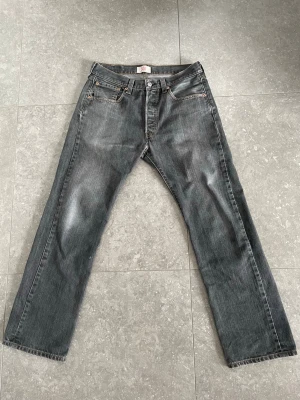 Grå raka jeans från Levi's - Levi's 501 jeans med rak passform . Jeansen har en snygg tvättad look och lite slitningar vid hälen. Storlek 32/30 men skulle säga att de sitter mer som 31/30.