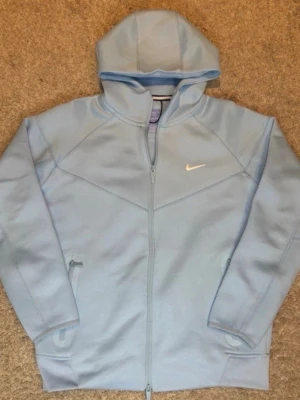 Ljusblå NOCTA hoodie från Nike - Ljusblå hoodie från Nike NOCTA-kollektionen med dragkedja framtill och två fickor.