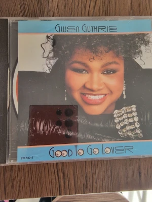 CD Gwen Guthrie Good To Go Lover - CD-album med Gwen Guthrie, 'Good To Go Lover'. Omslaget har en färgstark design med blå och orange detaljer. Albumet innehåller åtta låtar och ges ut av Polydor. Perfekt för dig som gillar soul och 80-talsmusik.