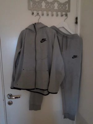 Nike Tracksuit grå stl 158–170 barn bra skick - Clean Nike tracksuit i grå färg 👕 — funkar perfekt till både vardag och aktivitet. Bekväm passform och mjukt material gör den enkel att använda varje dag, samtidigt som den stilrena designen ger en snygg sportlook 🔥 Storlek 158–170 och i bra skick. Komplett set med zip-hoodie och matchande byxor. Snabb affär prioriteras 📩