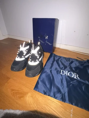 Svarta sneakers med reflexdetaljer - Snygga svarta sneakers med vita och reflekterande detaljer. Skorna har en chunky sula, meshpaneler och klassiska snörningar. Kommer med originalkartong och dustbag. Perfekta för dig som vill ha en exklusiv och trendig look.