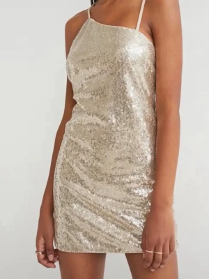 Glittrig kort paljettklänning strl 32 - Snygg kort klänning med tunna axelband, täckt av glittriga paljetter i en champagnefärgad ton. Klänningen har en rak passform och är perfekt för dig som vill sticka ut. Materialet känns mjukt mot huden och ger en lyxig känsla.