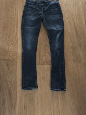 Mörkblå slim fit jeans dondup - Snygga mörkblå slim fit jeans med klassisk femficksdesign och lätt slitna detaljer. Jeansen har normal midja och smala ben, perfekta för en trendig och avslappnad look. Passar till det mesta och är ett måste i garderoben.