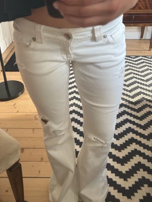 Vita bootcut jeans med slitningar - Säljer ett par vita bootcut jeans med slitningar från Gina! Helt nya och inga defekter!! Storlek S