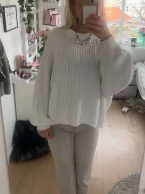 Vit  stickad tröja - Säljer en vit oversized stickad tröja med breda ballongärmar och rund hals. Tröjan har en grovstickad struktur och är perfekt för lager på lager. Passar dig som gillar en avslappnad och trendig stil. Skulle inte säga stt den är i storlek L, jag har Xs eller S i normala fall. Och är 174 cm lång 