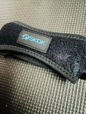 Prisförslag- NY! Mot Smärta i knät Svart träningsband löpning - Om man har ont i knät så är detta stöd jättebra och kan även användas när man springer. Det är svart träningsband från SKDK, tillverkat i slitstarkt tyg med kardborrestängning. Perfekt för träning och stöd, med blå insida och justerbar passform. Stilig design med SKDK-logga i blått på svart bakgrund.