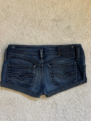 Mörkblå jeansshorts från Diesel - Oseriösa prisförslag nekas direkt, va en seriös köpare om du ska lämna prisförslag. Midjemåttet rakt över : 39 cm och längden på shortsen : 22cm. Står ej storlek i shortsen. Köpta för 450 kr. Två nitar har lossnat se bild 4.