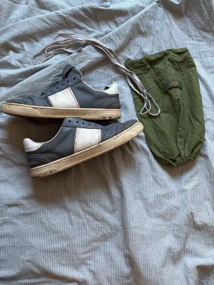 Valentino Flycrew  - Snygga äkta sneakers från Valentino i blå/grått och vitt läder med klassisk låg silhuett. Yttersulan har ett unikt kamouflagemönster och skorna kommer med vita skosnören samt en grön dustbag. Helt okej skick, pris kan diskuteras till viss grad. Storlek 42.5